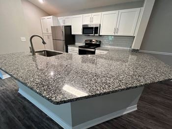 A kitchen with an island with granite counter top
